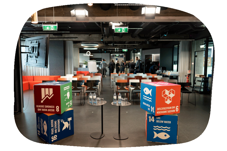 Cubes with the SDGs are on each side of a speaker's podium. Event guests can be seen in the background.