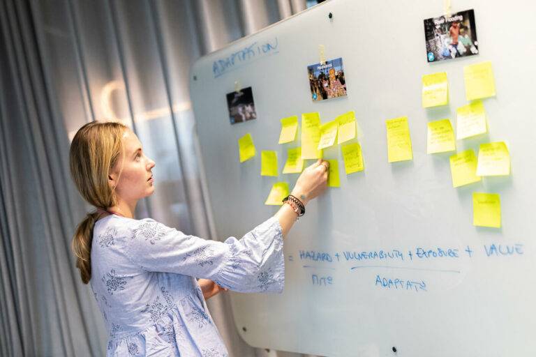 Eine Frau steckt Post-Its auf einem Whiteboard